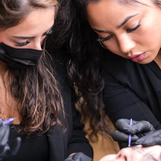 Instructor supervising a student performing a microblading procedure on a live model at Brow Lady Studio